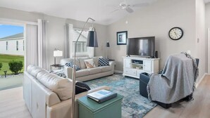 A modern living room with a sofa, a coffee table, a TV, and a ceiling fan.