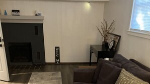 A living room with a brown sofa, a wooden coffee table, a fireplace, and a 'WELCOME' sign. - Oasis Studio Downtown Cambridge (Cambridge)