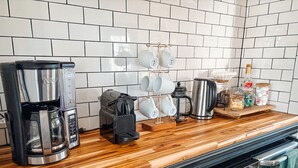 Eine Küche mit Holztischplatte, einer Kaffeemaschine, einem Wasserkocher, einem Toaster und einem Becherhalter.