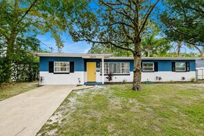 A single-story house with a front door, a garage, and a tree in the yard.