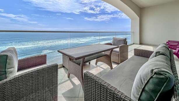 A balcony with wicker furniture, a table, and a view of the ocean. - MarYSo- Condo-BeachAccess-3BR-6th FLR-Rosarito (Playas de Rosarito)