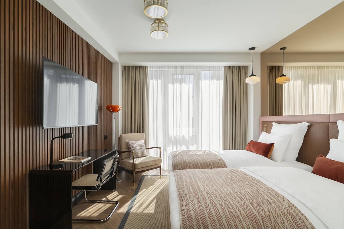 A hotel room with a bed, a chair, a desk, and a TV.