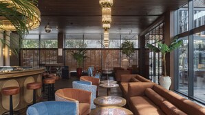 Ein moderner Lounge-Bereich mit Sitzgelegenheiten, Barhocker und großen Fenstern mit Ausblick.