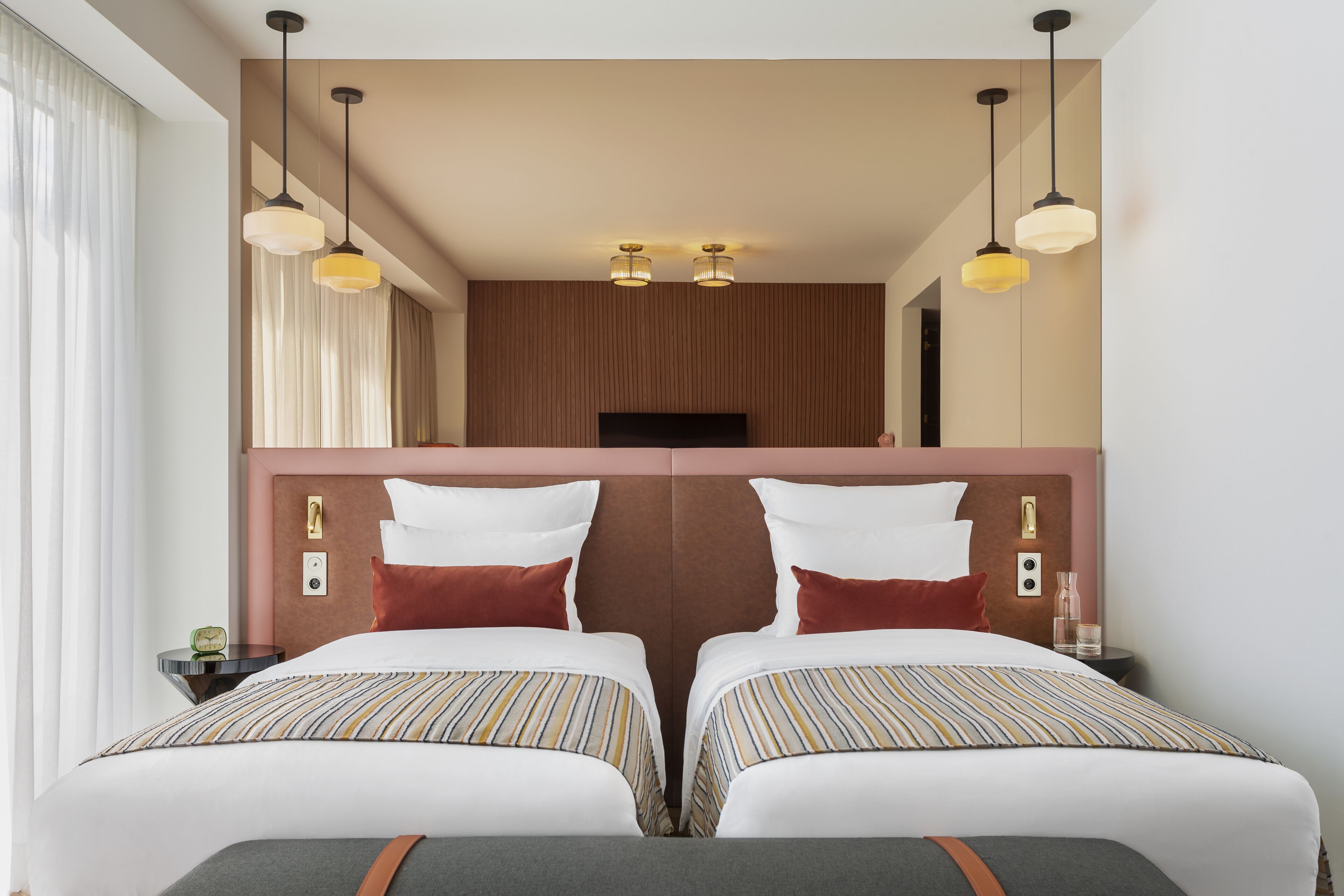 A hotel room with two beds, a large mirror, and a flat-screen TV.