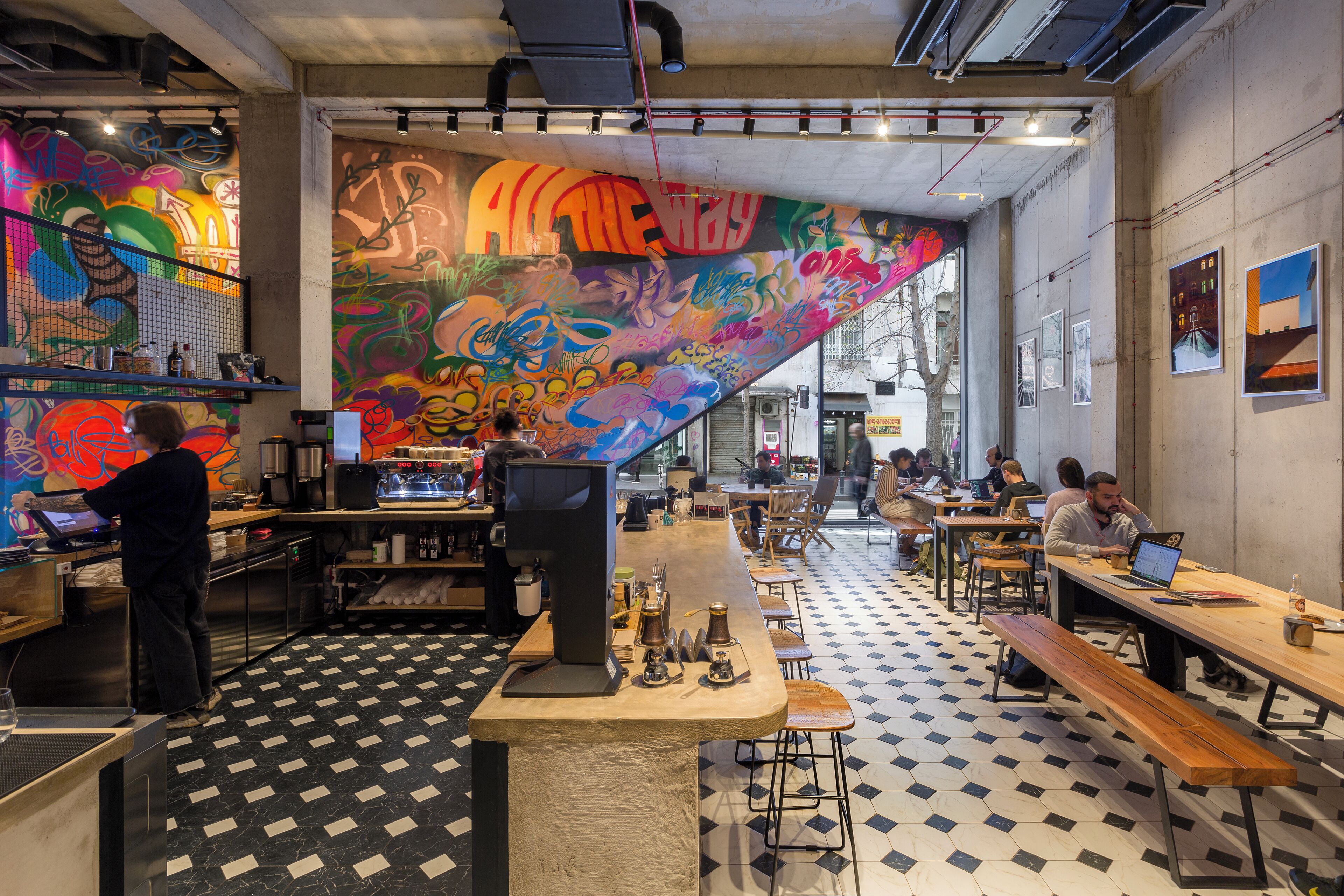 A café with a checkered floor, a bar area, and a mural on the wall.