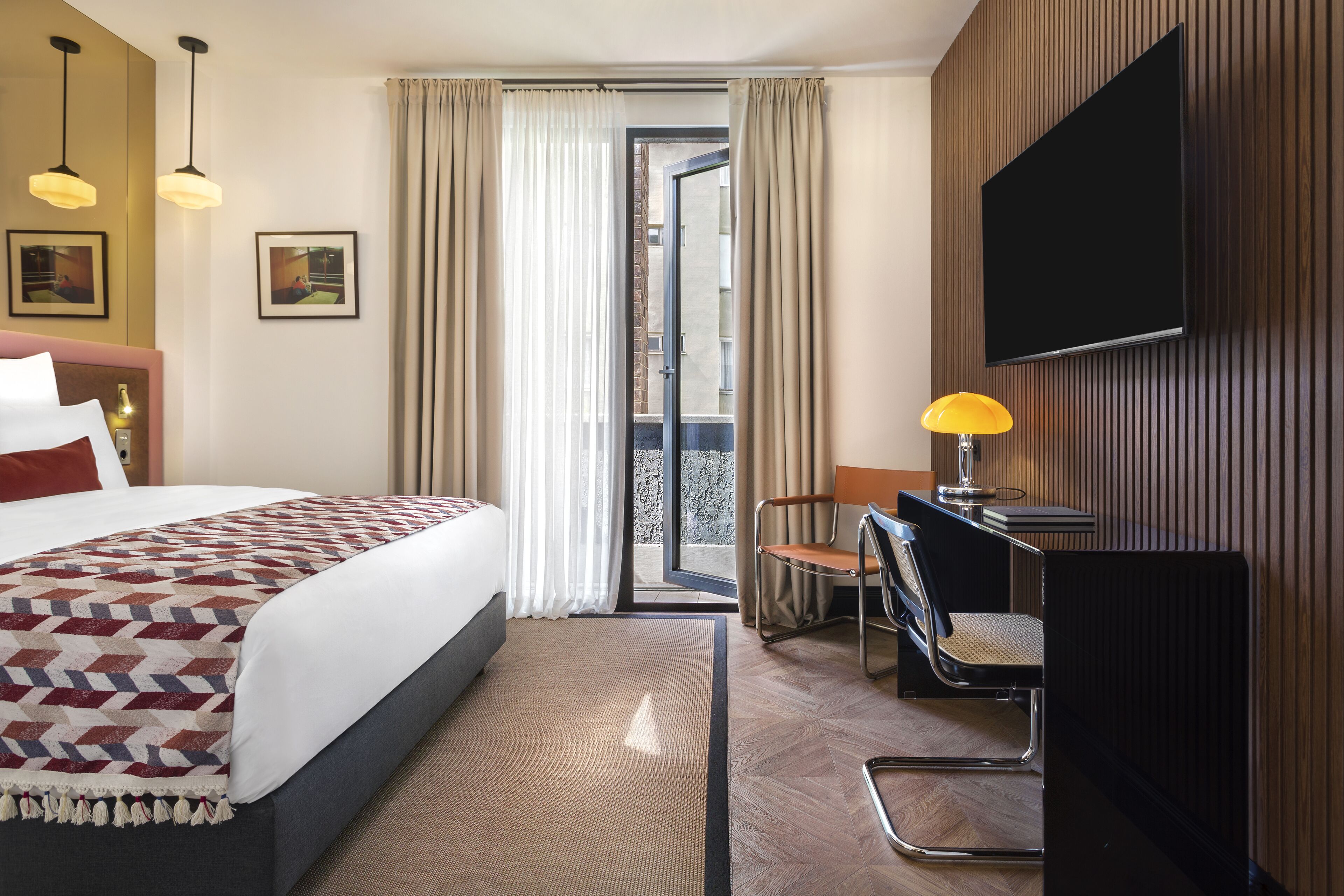 Una camera d'albergo con un letto, una scrivania con una sedia, una televisione e vista all'esterno.