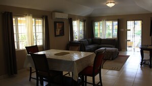A dining area with a table and chairs, a sofa, and a television. - Soleil Hartland Palms (St. Ann's Bay)