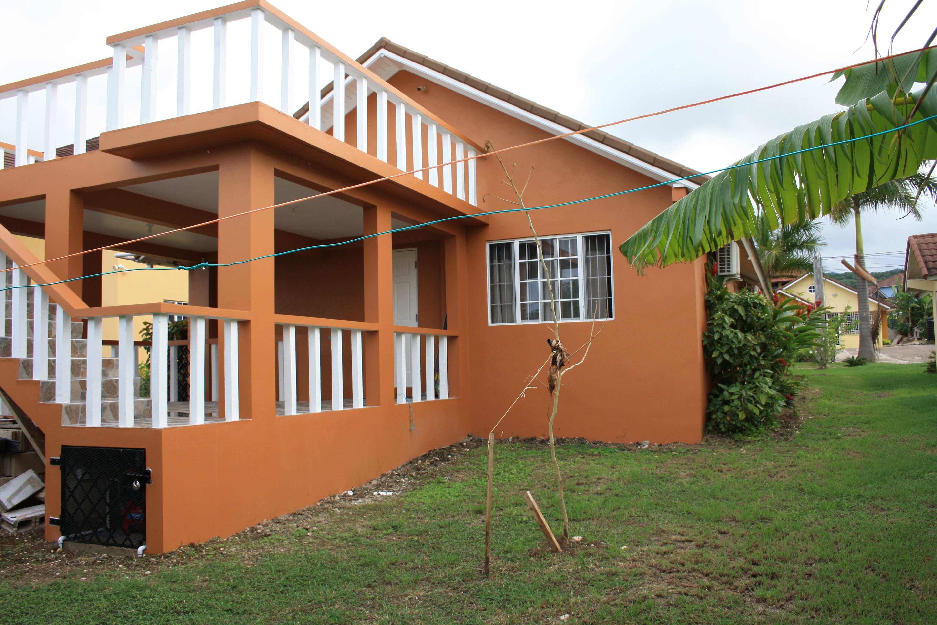 Una casa de dos plantas con un balcón y un pequeño jardín.