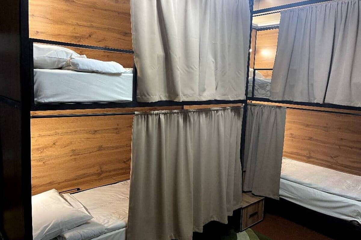 A dormitory-style room with bunk beds, each with a white mattress and matching pillow.