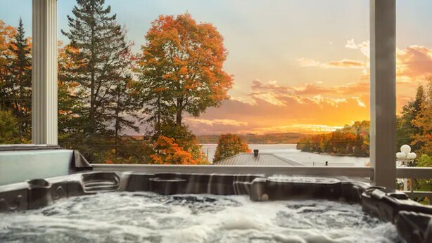 Un jacuzzi con vista a árboles y un atardecer.