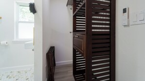 A narrow hallway with a wooden staircase, a radiator, and a window with blinds. - Stylish Group Retreat • Hot Tub • Game Room • Yard (Austin)