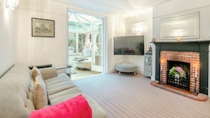 Una sala de estar con sofá, chimenea, televisor y un ventanal grande.