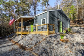 A cabin with a porch, a green door, and a flag. - Grace Point Cottage (Benton)