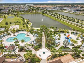 A resort with multiple swimming pools, a central fountain, and a water park area.