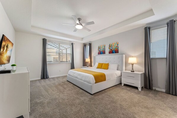 A modern bedroom with a large bed, a ceiling fan, and two bedside lamps.