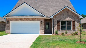 A two-story brick house with a garage, a small front yard, and a clear blue sky. - Charming Brand New Home in Foley (Foley)