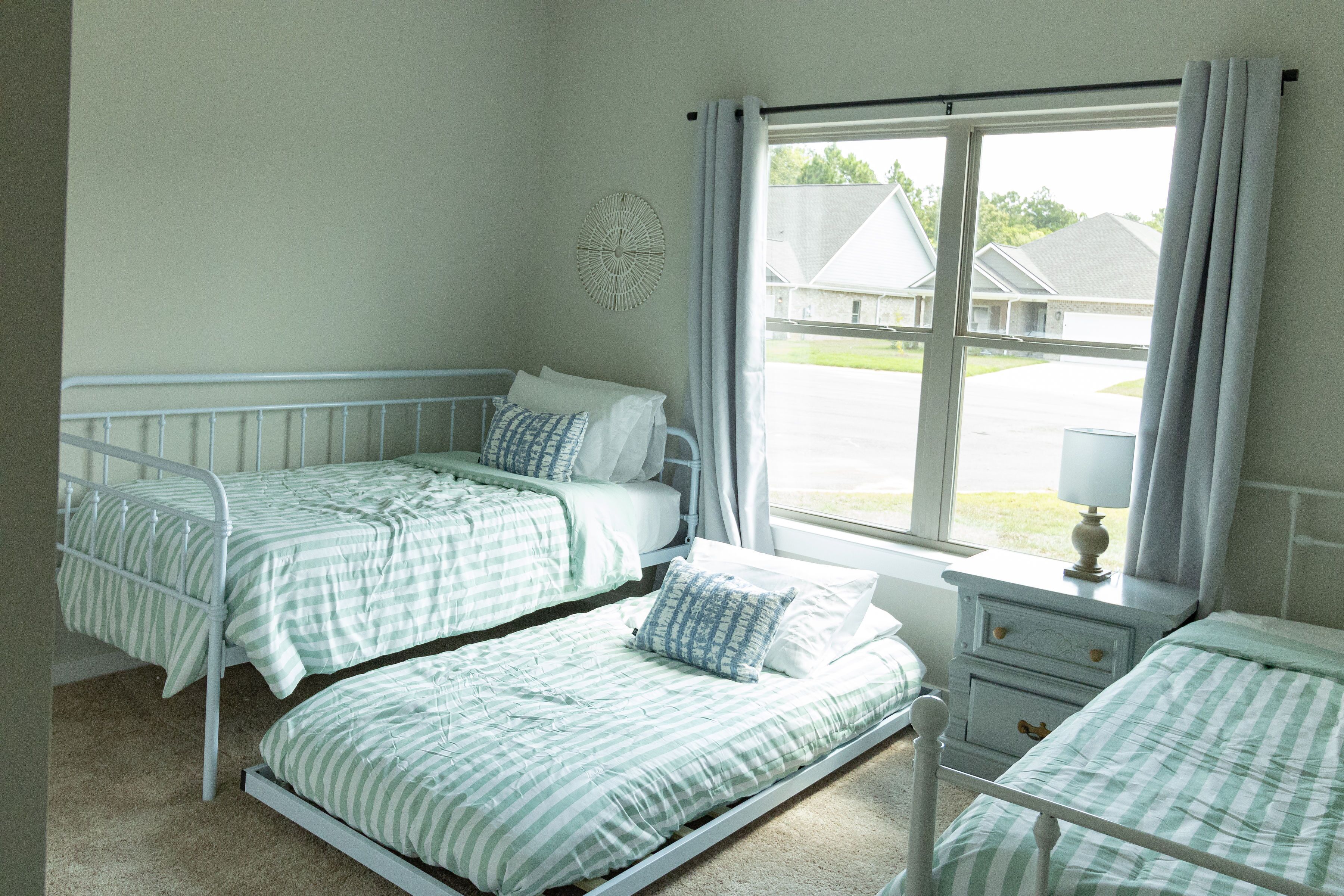 A room with two single beds, a small bedside table with a lamp, and a window with curtains.
