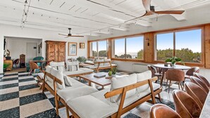 Una habitación amplia con piso a cuadros, muebles de madera, ventanas grandes y vistas al exterior.