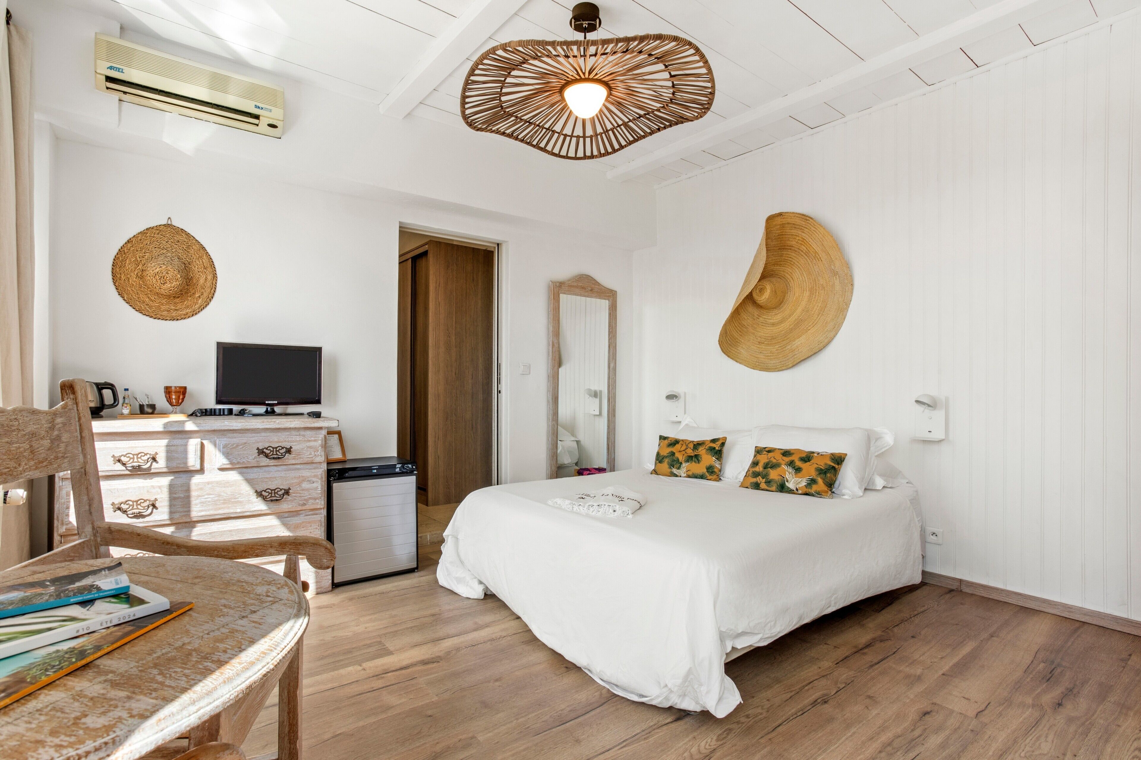Une chambre à coucher comprenant un lit, un bureau, une chaise, un téléviseur et un climatiseur fixé au mur.