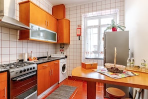 Une cuisine avec des meubles de rangement en bois, une cuisinière, un lave-linge et un réfrigérateur.