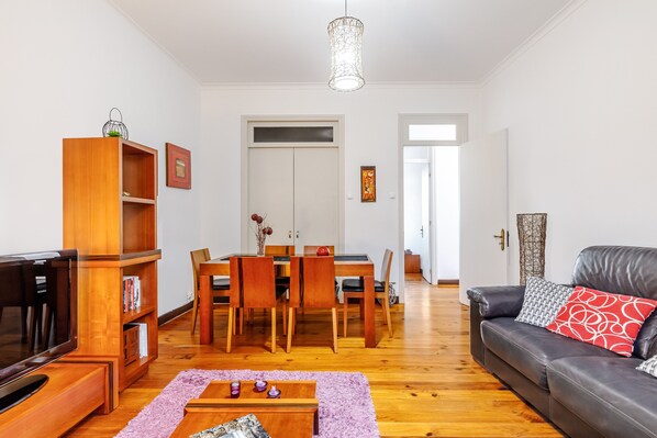 Un salon avec un téléviseur, des meubles en bois, une table à manger et un canapé en cuir.