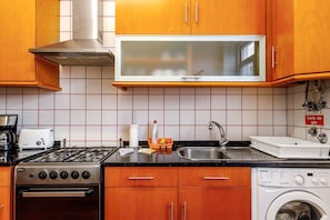 Una cocina con armarios de madera, estufa de acero inoxidable, microondas y lavadora.