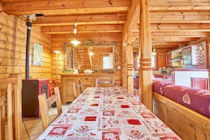 Interior de una cabaña de madera con una larga mesa de comedor, un espejo y una zona de cocina.