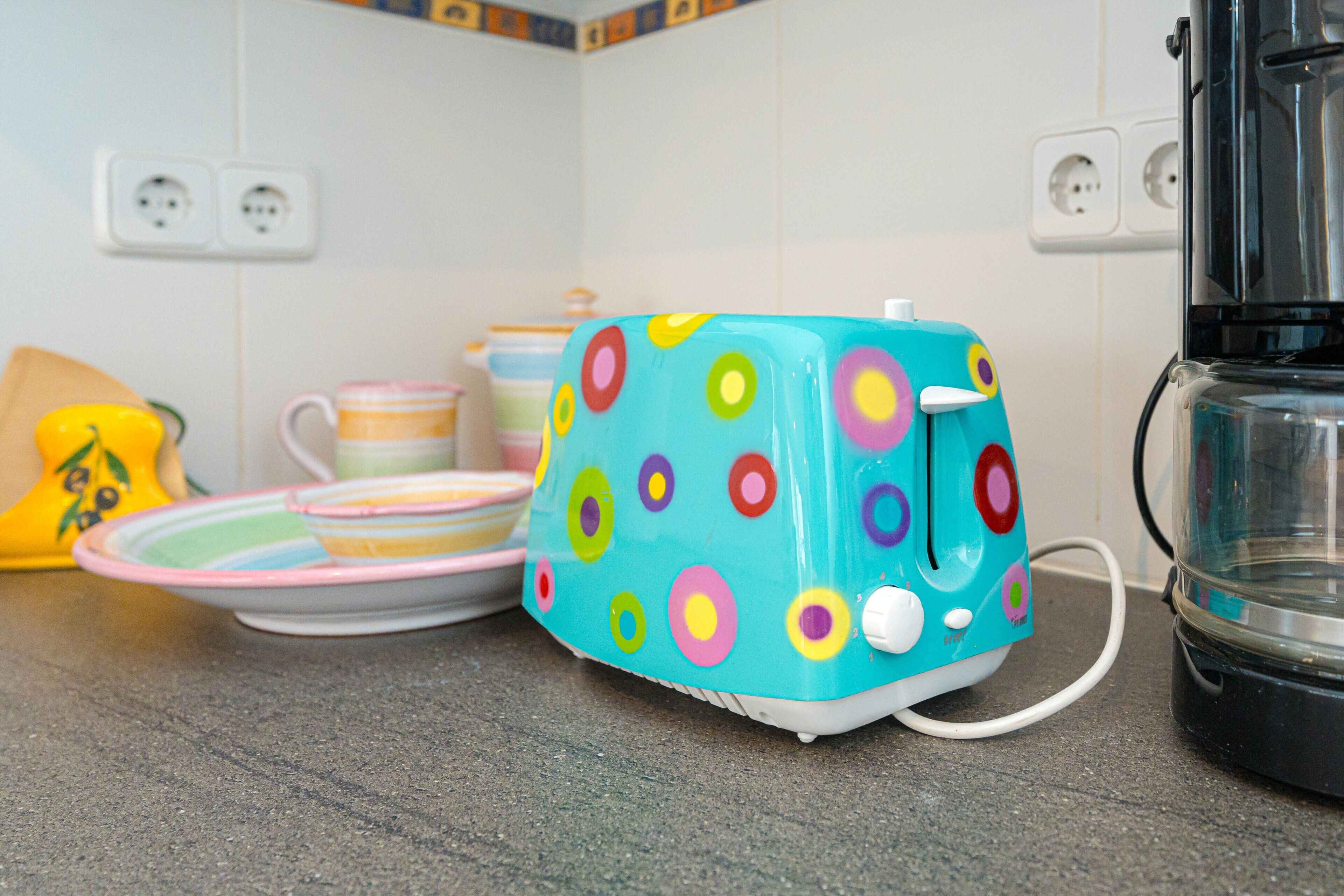 A kitchen counter with a colorful toaster, a coffee maker, and various kitchen items.