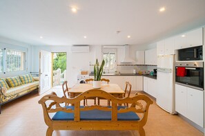 A modern kitchen with white cabinets, a wooden dining table, and a built-in microwave.