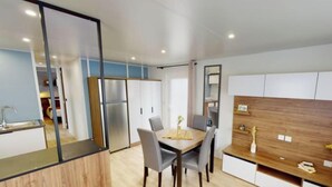 A modern kitchen with a dining table, chairs, a refrigerator, and wooden cabinets.
