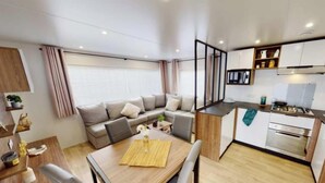 A modern, compact living space with a kitchenette, a dining area, and a sofa set.