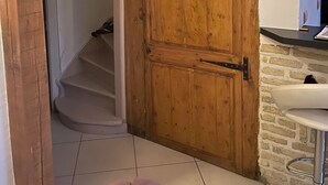 Eine Holztreppe führt zu einem Raum mit einer weißen Tür, einer Steinwand und einer Bar mit einem Waschbecken.