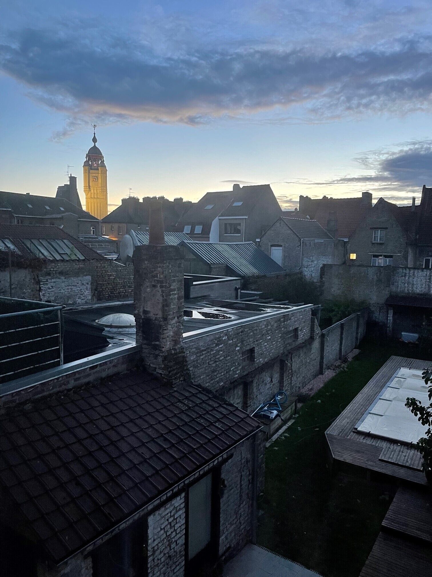 Un cortile con edifici in pietra, una torre dell'orologio e un'area giardino.
