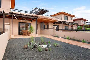 A modern house with a patio, outdoor seating, and a garden with cacti.