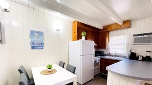 A compact kitchen with a white refrigerator, wooden cabinets, and a small dining area with a table and chairs. - Cozy one bedroom across from the beach #2 (North Myrtle Beach)