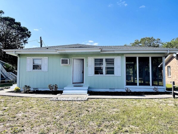 A single-story house with a front porch, a small front yard, and a clear sky.