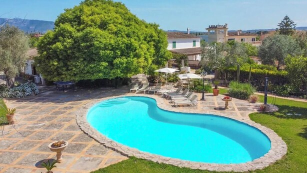 Une piscine bordée de pierres, entourée d’une pelouse et d’arbres.