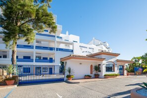Un hotel con fachada blanca, detalles azules y un letrero que dice 'DUQUESESA SUITES'.