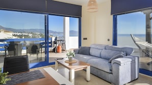 Un salon moderne avec un canapé, une table basse et une vue sur l’océan.