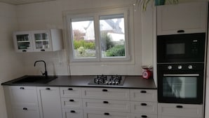 A kitchen with white cabinets, a black countertop, a sink, a window with a view, and a red scale.