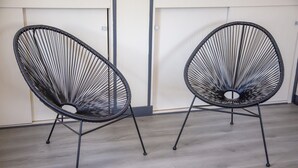 Two black wire-framed chairs with metal legs on a light wooden floor.