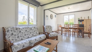A living room with a sofa, armchairs, a coffee table, and a dining area with chairs and a table.