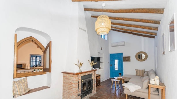 Ein Wohnzimmer mit Kamin, einer blauen Tür, einem Sofa und einer Hängeleuchte.