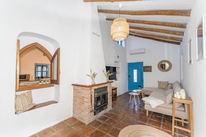 Una sala de estar con chimenea, una puerta azul, un sofá y una lámpara colgante.