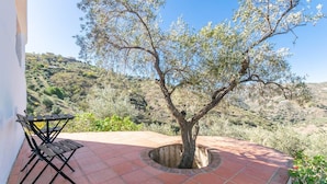 Eine Terrasse mit Baum, Tisch und Stuhl.