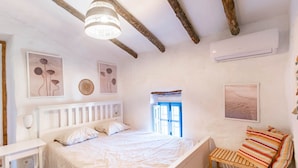 Ein Schlafzimmer mit einem Bett, einem Nachttisch, einem Fenster und Wandbildern.
