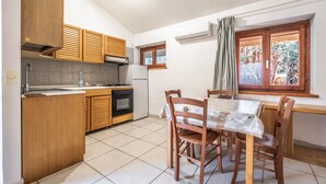 Une cuisine de taille réduite, dotée de meubles en bois, d’une cuisinière et d’un coin repas avec une table et des chaises.