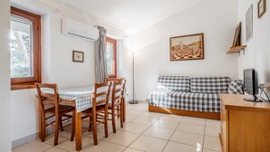 Una habitación con una mesa de comedor, sillas, un sofá, un televisor y un cuadro en la pared.