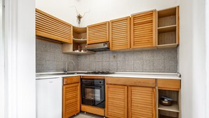 Una cocina con armarios de madera, estufa a gas, horno y lavavajillas.