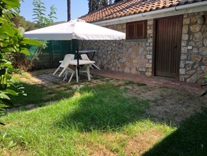 A stone building with a tiled roof, a wooden door, and a patio with a table and chairs. - Apartment 'La Capannuccia D' with Sea View, Wi-Fi and Air Conditioning (Ansedonia)
